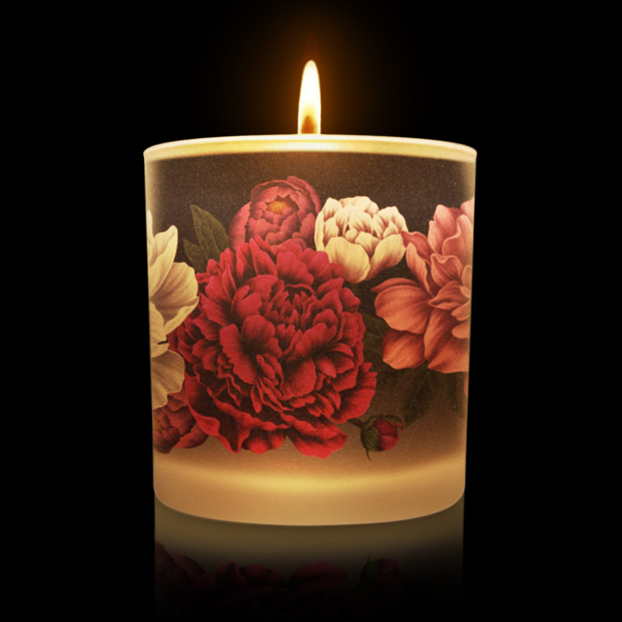 Lit candle with floral design on a black background