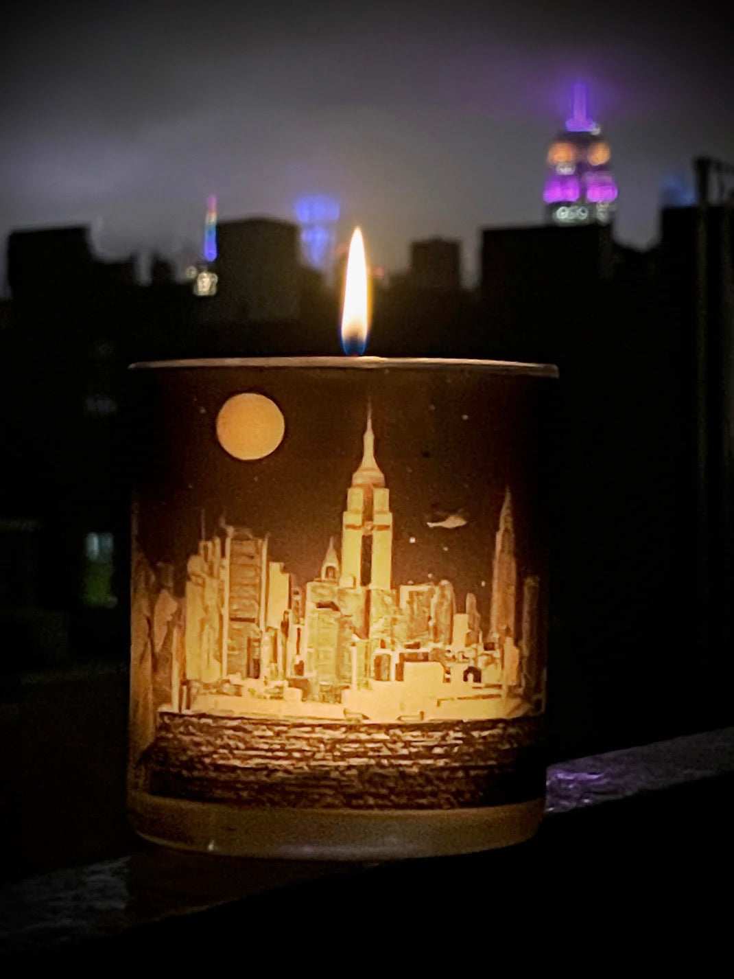  Night shot of glowing NYC candle with city skyline 